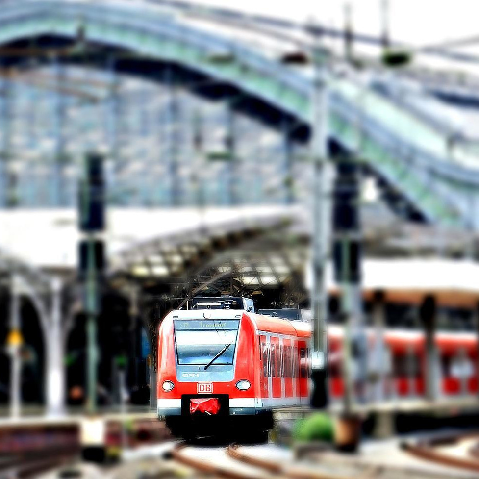 Ein Foto eines roten Regionalzuges der einen großen Bahnhof verlässt