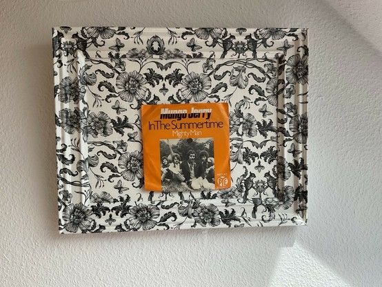 Ein mit schwarz weißem romantischen Muster dekopagiertes Bild (incl Rahmen) , in der Mitte wurde mittels kleiner Magneten ein Single-Cover von  Mungo Jerry : Mighty man aufgebracht