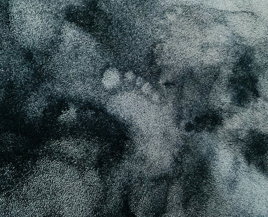 Auf einem wuscheligen türkisgrauen Teppichboden der Schemen eines Fußes, besonders die Zehen sind gut abgebildet. 
Wie ein Fuß-Geist. 