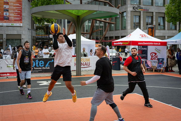Ein Spieler springt und wirft den Basketball in Richtung des Basketball-Korbs.