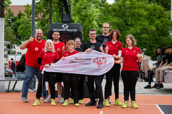 Daniel R. Schmidt steht links von einer Gruppe Sportler:innen der Special Olympics Hessen.