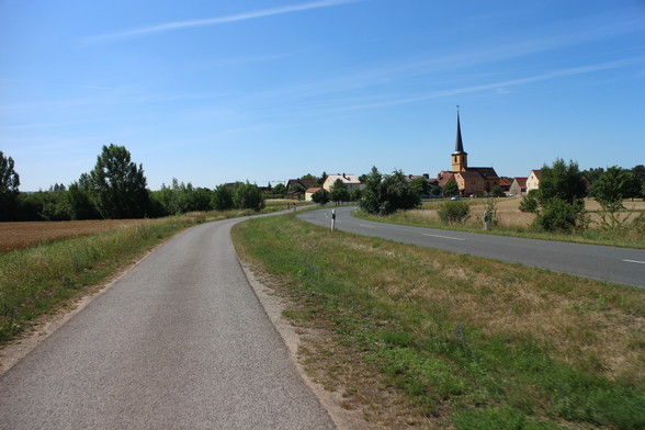Radweg außerorts an Landstr. mit Dorf im Hintergrund. Ist Symbolbild.