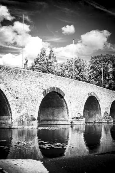 In schwarz-weiß: im Vordergrund, eine Brücke mit Bögen, die sich über die Lahn spannt. Im Hintergrund ist der Wetzlarer Dom zu sehen.