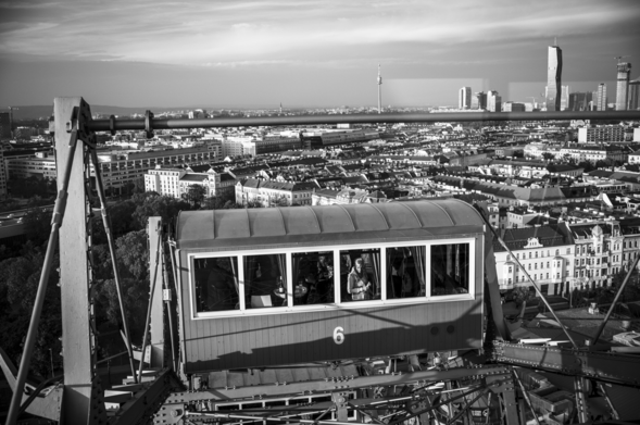 Vom Wiener Riesenrad aus aufgenommen: eine weitere Kanzel. Eine Person schaut daraus nach unten. Im Hintergrund die Weite von Wien mit unendlich vielen Gebäuden