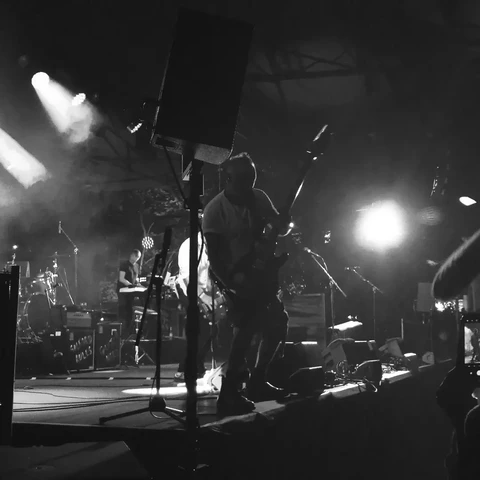 Peter Hook on stage, swinging the bass guitar.