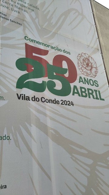 Ein weißes Plakat, zum 50. Jubiläum der Nelkenrevolution in Vila do Conde, Portugal. Darauf groß zu sehen in grüner und roter Schrift die Zahlen 25 und 50.