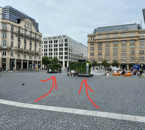 Großansicht des Goetheplatzes in Frankfurt. Der Platz besteht vollständig aus Kopfsteinpflaster. Auf dem Patz stehen zwei mobile Grünzeug-Wände auf Paletten (Einzelheiten siehe andere Bildbeschreibung).