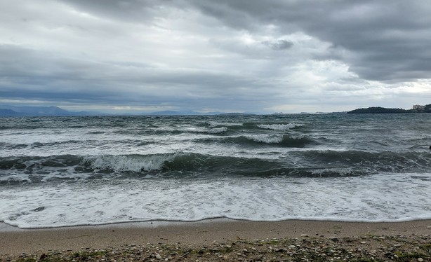 Strand, Meer mit Wellen, Wolken und grauer Himmel