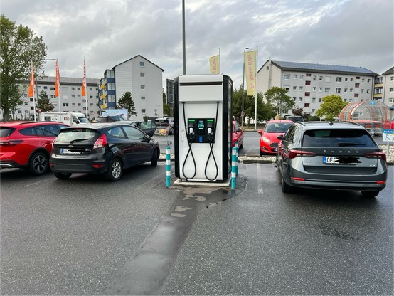 Ladesäule für E-Autos mit zwei Ladepunkten, beide von Verbrennern zugeparkt.