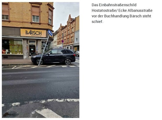 Links das Foto eines Gebäudes an einer Straßenecke. Direkt an der Ecke steht ein schwarzes Kfz und davor ein schief stehender Schildermast.
Rechts der Text 