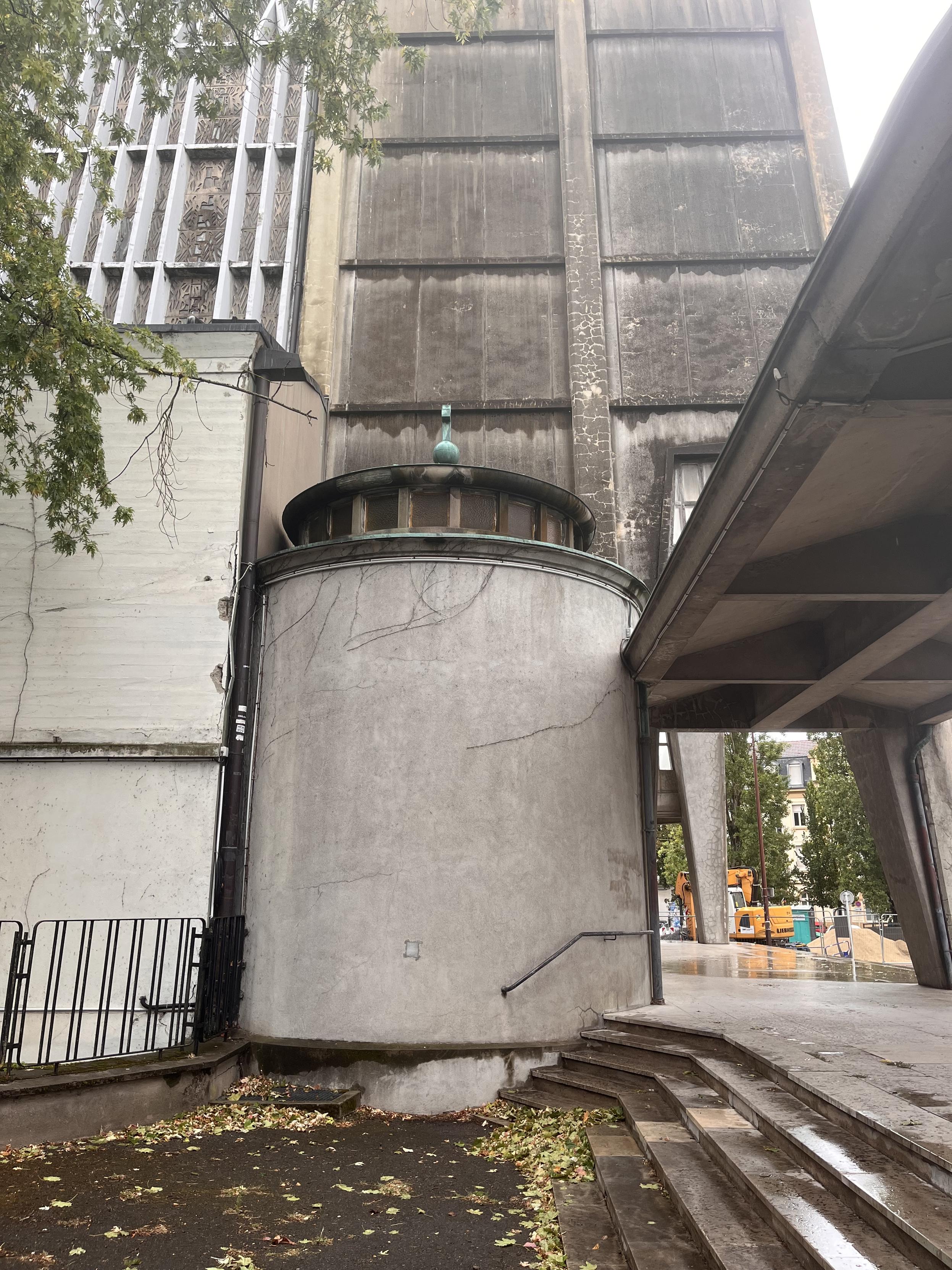 Une annexe latérale semi-circulaire adossée à l'église Sainte-Thérèse ; le mur est plein, le toit est percé de petites fenêtres carrées disposées en rayons.