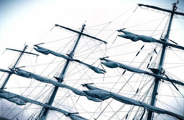 Querformat: Ausschnitt der Takelage eines großen Dreimaster-Segelschiffs. Die Segel sind eingepackt und die Masten und das komplizierte Netz aus Seilen sind im Detail zu sehen. Das Bild ist in einfarbigen Graublautönen gehalten und wird durch vertikale Linien von Masten und diagonalen Tauen strukturiert.