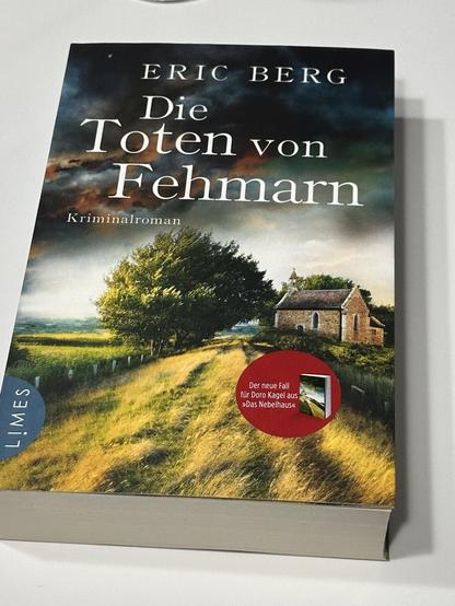 Das Cover des Kriminalromans „Die Toten von Fehmarn“ von Eric Berg.
- Titel: „Die Toten von Fehmarn“ in prägnanter Schrift, Autor Eric Berg.
- Bildmotiv: Ein Feldweg führt zu einer kleinen Kirche in der Ferne. Der Himmel ist bewölkt und dramatisch. Im Vordergrund wachsen hohes Gras und einige Bäume.
- Aufkleber: Ein roter Aufkleber mit dem Text „Der neue Fall für Doro Kagel aus ‚Das Nebelhaus‘“.
- Verlagslogo: „LIMES“ in der unteren linken Ecke.
- Farben: Vorwiegend Grün, Gelb und Blau.
Die Sti…