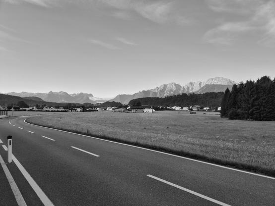Landstraße im  Vordergrund, Dorf und Berge im Hintergrund. Salzburger Land bei Adnet. 